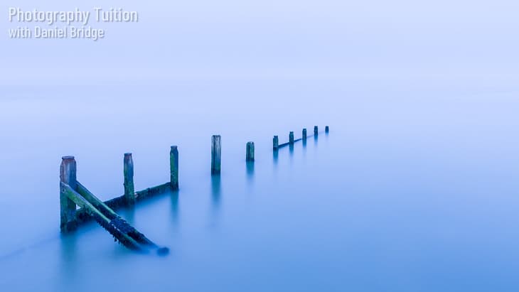 A long-exposure shot of a breakwater with cool blue tones.